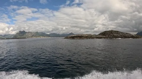 Boat passing close to rocky islet with mountain range background Lofoten Stock-Footage 344047456