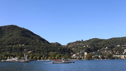 Boat passing by on Como lake with mountain on the background in a sunny day Stock Footage 116113686