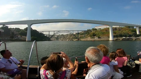BOAT WITH PEOPLE ACROSS THE DOURO RIVER APPROACHES TO FREIXO BRIDGE, PORTO Stock Footage 95943012