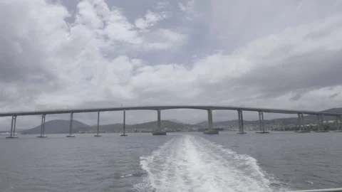 Boat POV Approaching Large Arched Bridge Over Bay with Wake Trail Stock Footage 328190948
