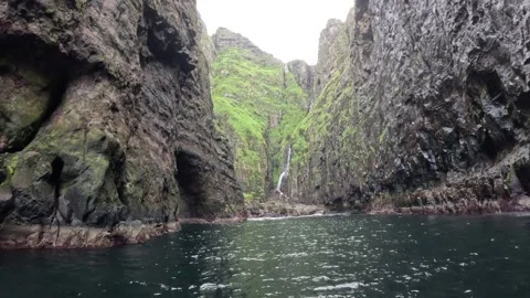Boat POV of a hidden waterfall cascading inside a dramatic sea gorge Stock-Footage 339289155