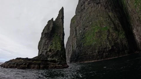 Boat POV passing a sharp basalt sea stack needle in Vestmanna, Faroe Islands Stock Footage 339318711