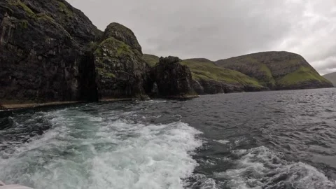 Boat POV sailing away from dramatic bird cliffs with powerful ocean wake Stock-Footage 339289144