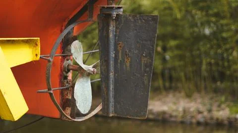 Boat propeller and rudder assembly mounted on hull near water Stock Photos