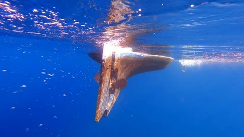 Boat propeller spins steadily underwater beside rudder while engine - Hardware Stock Footage 339976465