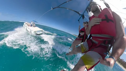 Boat pulling couple parasailing over ocean Stock Footage 87057894