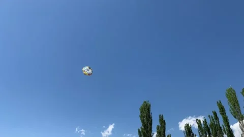 A boat pulls a parachute across the sea with two tourists flying over the shore. Stock Footage 202633361