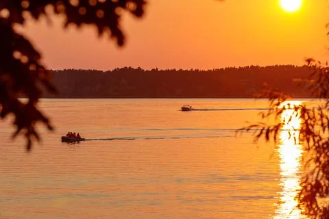 A boat pulls a person over the waves on a wakeboard. Wakeboarding at sunset Stock Photos