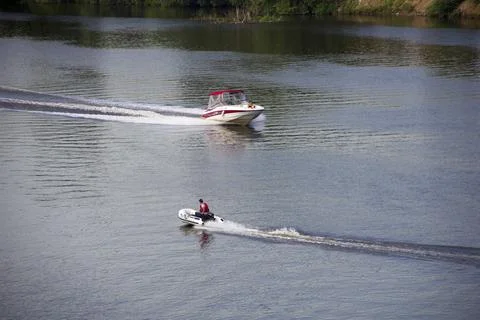 Boat on the river with a man on the background. View from above. Stock Photos