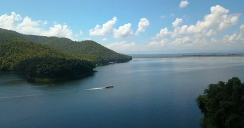 Boat running in a lake between mountains under fluffy clouds at national park Stock Footage 108469256