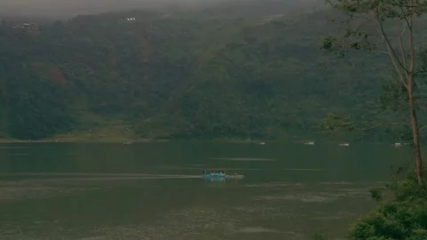 A boat sailing in the middle of a lake between misty mountains Stock Footage 288714531