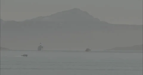 Boat sailing by, old ship and navy ship in background with mountains Stock Footage 211748334