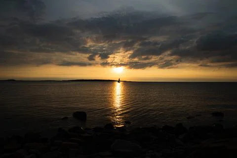 Boat sailing in the sunset dramatic cloudy sky Stock Photos