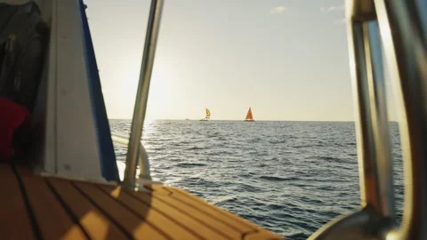 Boat Sailing Through Waves Towards Sail Boats Near the Sunset 4K Stock Footage 263370992