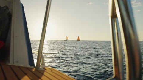 Boat Sailing Through Waves Towards Two Distant Sail Boats Near the Sunset 4K Stock Footage 263371237