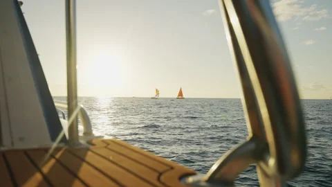 Boat Sailing Through Waves Towards Two Sail Boats by The Sunset 4K Stock Footage 263371898