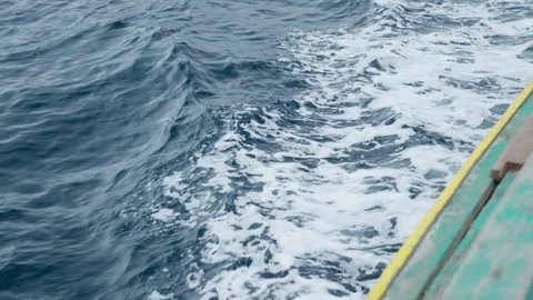 A boat sails across the ocean creating a trail of foamy waves behind it Video stock 328026791