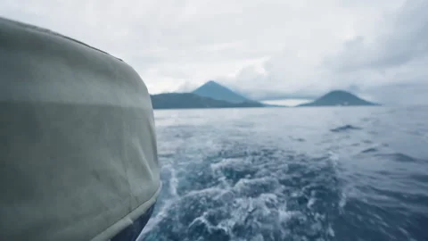 Boat sails across ocean towards distant mountains on a cloudy day. Video stock 328030296