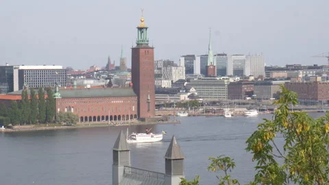 Boat sails down river in front of Stockholm City Hall on sunny day Vídeos de archivo 250879851