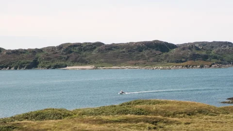 A boat sails in slow motion through two islands and wih calm seas Stock Footage 138411160