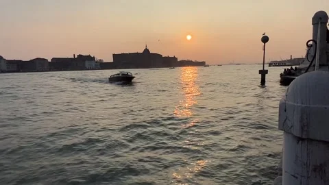 A boat sails at sunset through a canal in Venice Stock Footage 313224147