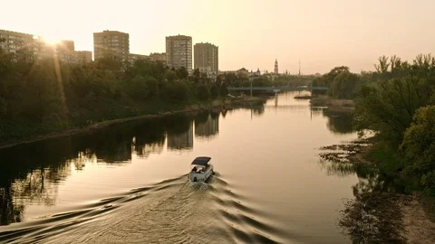 A boat sails though river waters during picturesque sunset Stock Footage 112034215