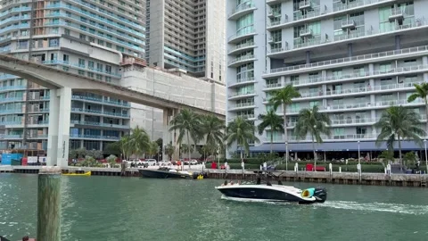 Boat sails through Miami river. People on Miami riverwalk. Downtown Miami 動画素材 328348265