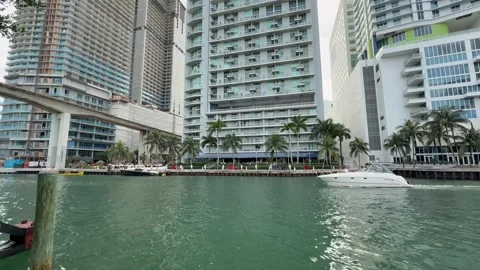 Boat sails through Miami river. People on Miami riverwalk. Downtown Miami Stock Footage 328348272