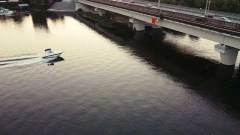 The boat sails under a bridge that runs the metro at sunset in urban areas. Stock Footage 140015757