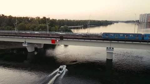 The boat sails under a bridge that runs the metro at sunset in urban areas. Stock Footage 140988211