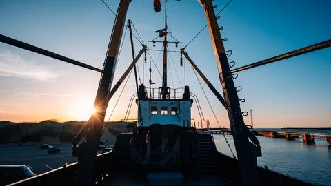 A boat is seen from the side with the sun setting in the background Stock Photos
