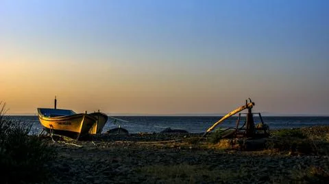 A boat on the shore posing to the camera while sun is falling down Stock Photos