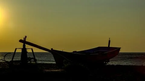 A boat on the shore posing to the camera while sun is falling down Stock Photos