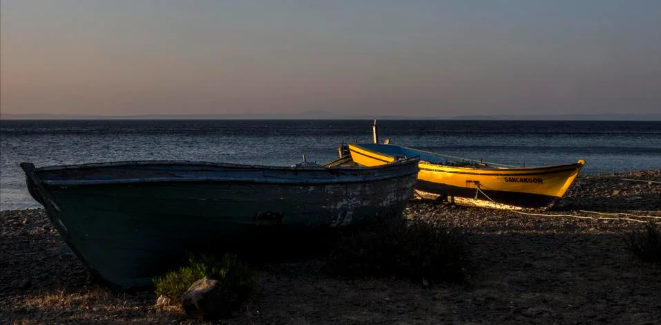 A boat on the shore posing to the camera while sun is falling down Stock Photos