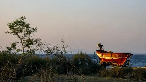 A boat on the shore posing to the camera while sun is falling down Stock Photos