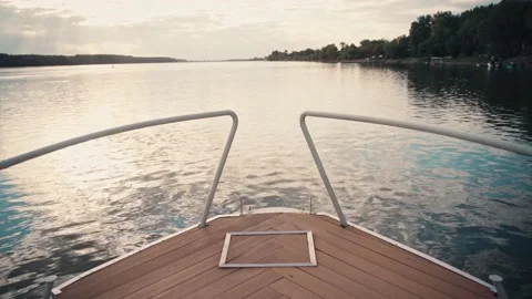 A boat slowly floats on the smooth surface of a river or lake during sunset. Stock Footage 218431541