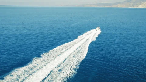 Boat speeding across the endless deep blue sea leaving white water trail under Stock Footage 344772455
