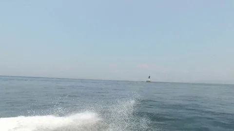 Boat Speeding Past Lighthouse in the Ocean Stock Footage 85078551