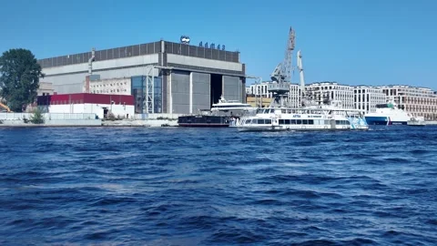 A boat speeds along the Neva River past the Almaz shipyard on a clear sunny day Stock Footage 313863136