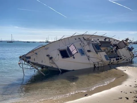 Boat stranded on the beach after a storm. On a sunny day with few clouds. Sai Stock Photos