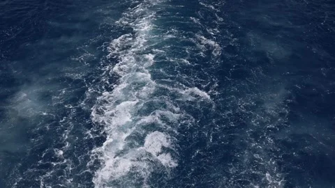 Boat trail deep blue water foamy waves sparkle in sunlight ocean texture motion  Stock Footage 310820456