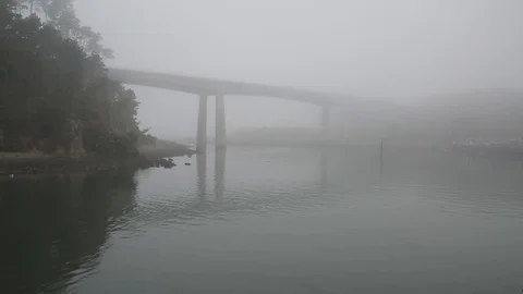 Boat travels into the fog underneath a bridge Stock Footage