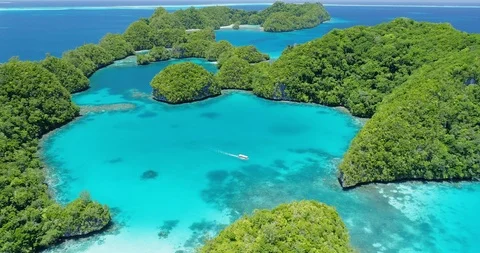 Boat travels slowly through tropical islands and turquoise lagoon in Palau Stock Footage