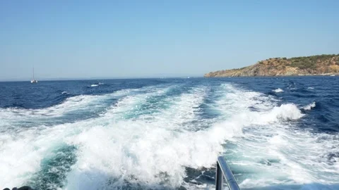 Boat trip leaving white trail on blue water near roses, girona Stock Footage 315867643