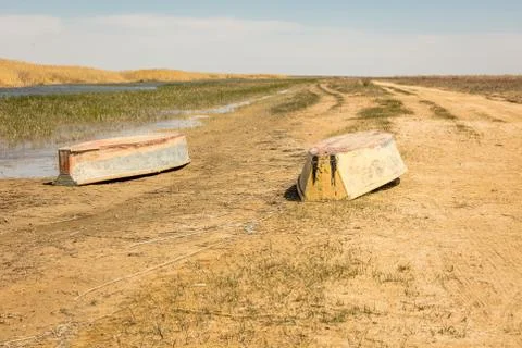 A boat turned upside down. Rowing boats in the reeds. Wooden boat on a grassy Stock Photos