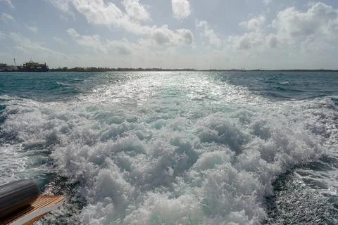 Boat wake creating white foam on blue sea Stock Photos