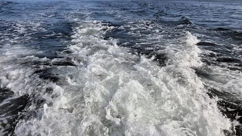 Boat wake cutting through dark open water Stock Photos