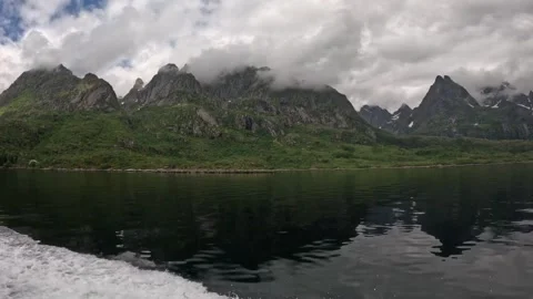 Boat wake navigating fjord passing lush mountain range reflection in Lofoten Stock Footage 344753103