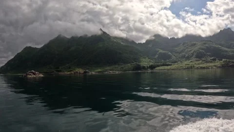 Boat wake navigating past dramatic cloudy green mountains in Lofoten Vídeos de archivo 344453305