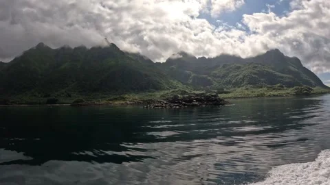 Boat wake passing small rocky islet and dramatic mountains in Lofoten Stock-Footage 344453330